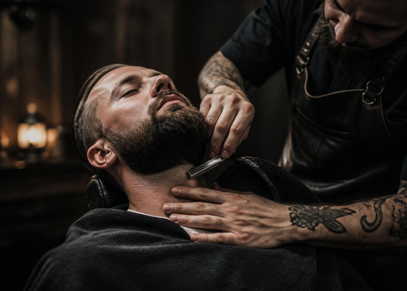 Barbeiro modelando a barba com navalha